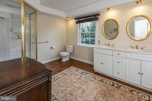 bathroom with vanity, toilet, a shower with shower door, and hardwood / wood-style floors