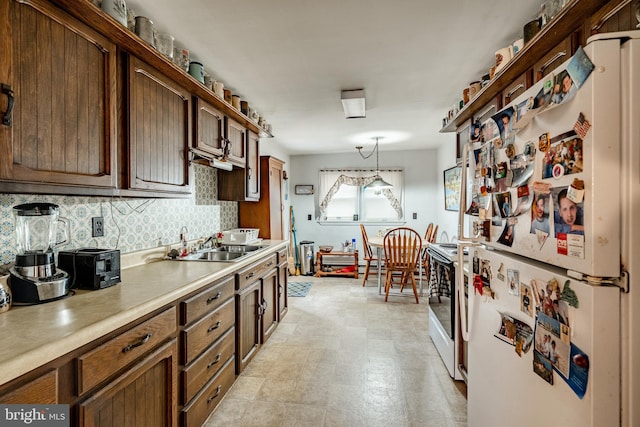 kitchen featuring pendant lighting, sink, white appliances, and backsplash