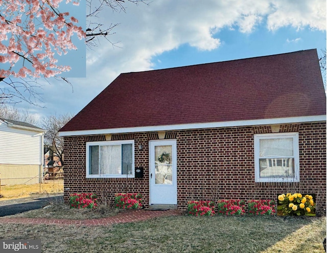 view of front of property featuring brick siding, a shingled roof, and a front yard