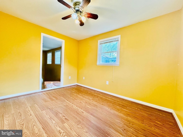 empty room with wood finished floors, baseboards, and a ceiling fan