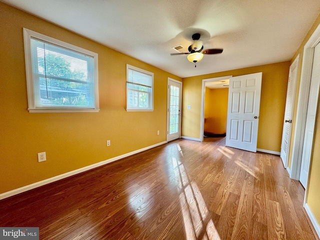 unfurnished bedroom with wood finished floors, baseboards, and access to exterior