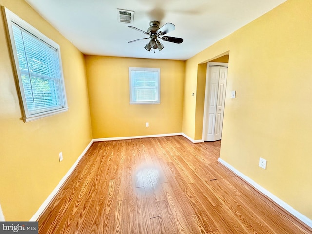 empty room featuring plenty of natural light, light wood-style floors, a ceiling fan, and baseboards