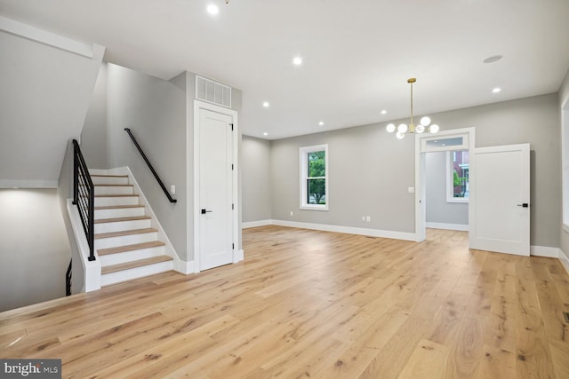 unfurnished living room featuring a chandelier and light hardwood / wood-style flooring