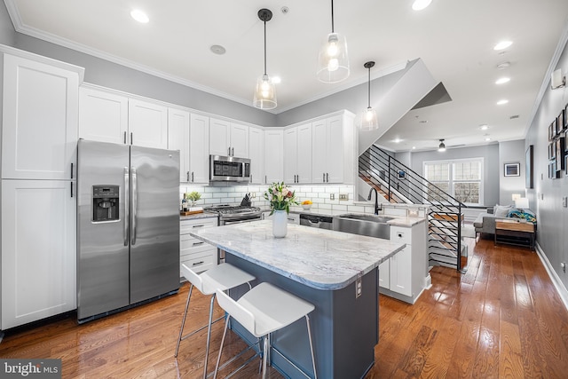 kitchen featuring white cabinetry, stainless steel appliances, a center island, and sink