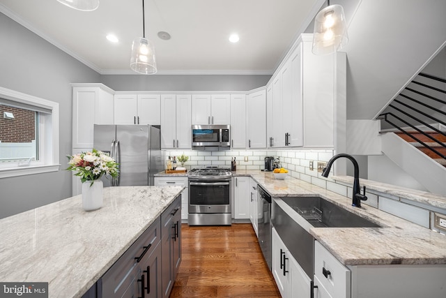 kitchen with hanging light fixtures, white cabinetry, appliances with stainless steel finishes, and light stone counters