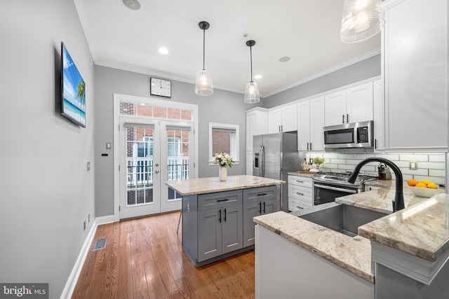 kitchen featuring french doors, white cabinetry, decorative light fixtures, a center island, and stainless steel appliances