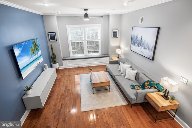 living room with wood-type flooring, ornamental molding, and ceiling fan