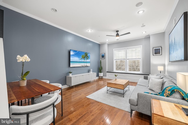 living room featuring hardwood / wood-style floors, ornamental molding, and ceiling fan