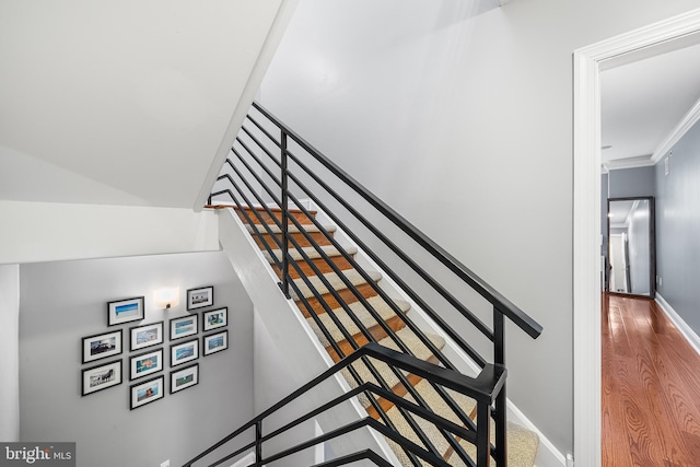 staircase with hardwood / wood-style floors and crown molding