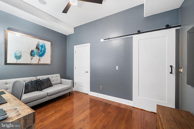 living room featuring a barn door, hardwood / wood-style floors, and ceiling fan