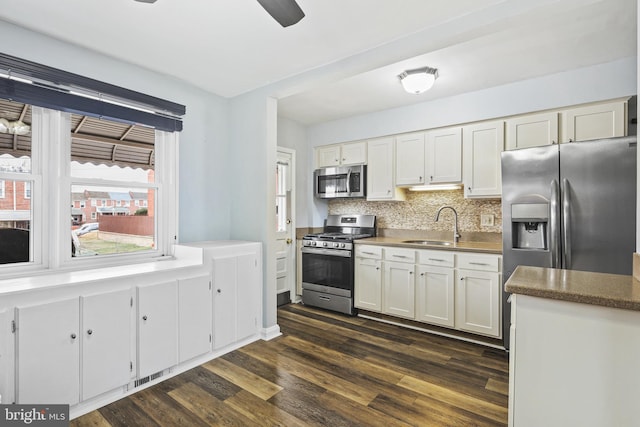 kitchen with dark wood-type flooring, a sink, white cabinets, appliances with stainless steel finishes, and backsplash