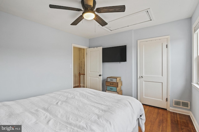 bedroom with ceiling fan, wood finished floors, visible vents, baseboards, and attic access