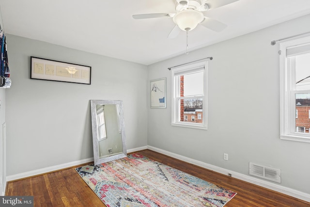 unfurnished room with baseboards, visible vents, ceiling fan, and wood finished floors