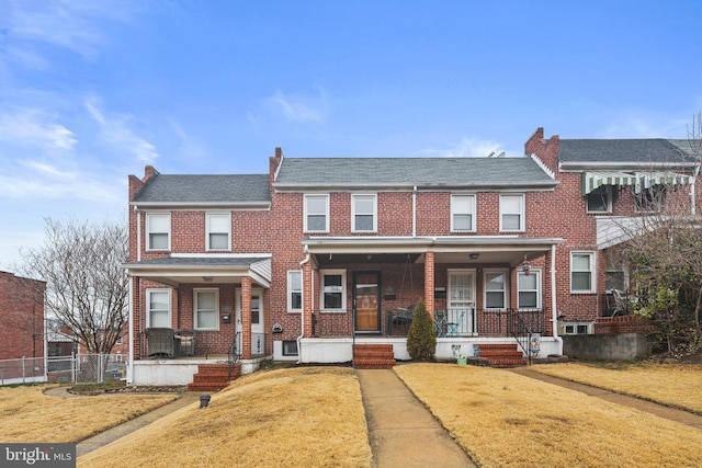 view of property with a front lawn, a porch, and brick siding