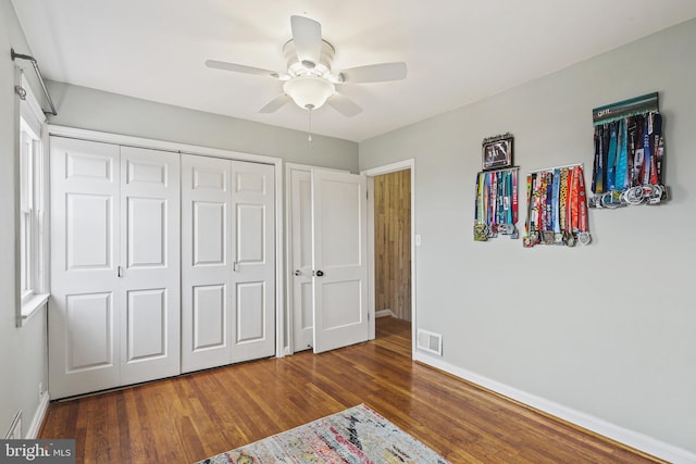 unfurnished bedroom featuring visible vents, ceiling fan, baseboards, and wood finished floors