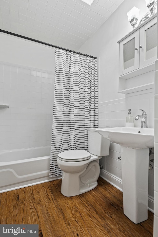 full bathroom with toilet, shower / tub combo, tile walls, and wood finished floors