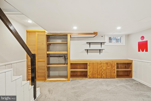 basement featuring carpet floors, recessed lighting, wainscoting, and stairs