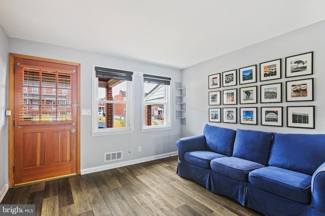 living area featuring visible vents, baseboards, and wood finished floors