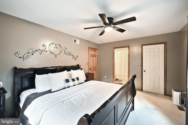 bedroom featuring ensuite bathroom, light colored carpet, and ceiling fan