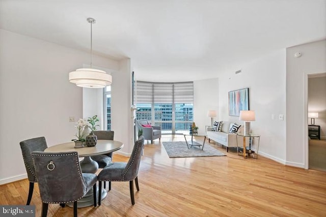 dining area with expansive windows, baseboards, and wood finished floors