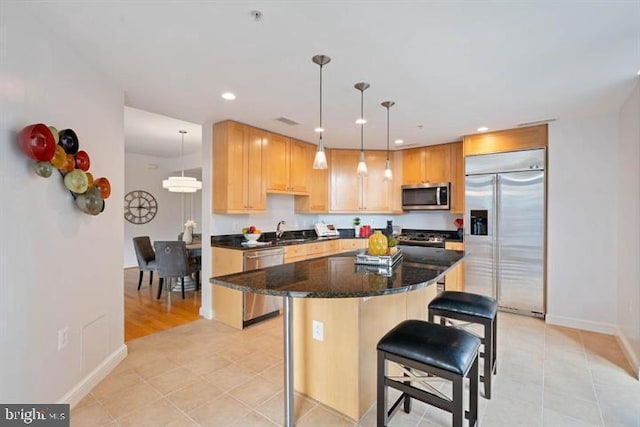 kitchen with a breakfast bar, dark stone countertops, a center island, stainless steel appliances, and recessed lighting