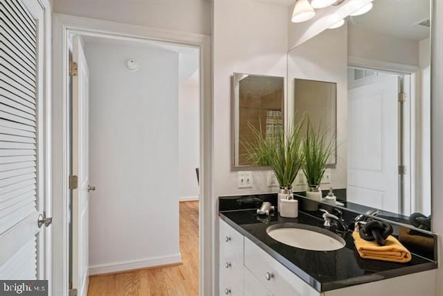 bathroom featuring baseboards, wood finished floors, and vanity