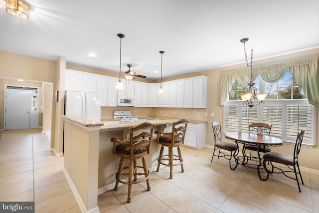 kitchen with white cabinetry, a center island, hanging light fixtures, white appliances, and decorative backsplash