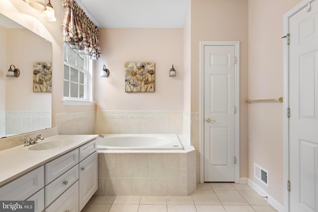 bathroom featuring tiled tub, vanity, and tile patterned floors