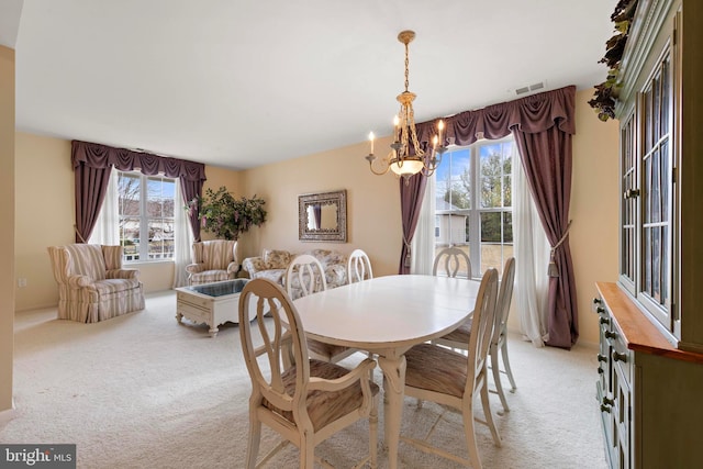 carpeted dining room featuring an inviting chandelier and a healthy amount of sunlight