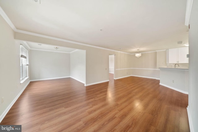 empty room featuring ornamental molding, a notable chandelier, and light wood-type flooring