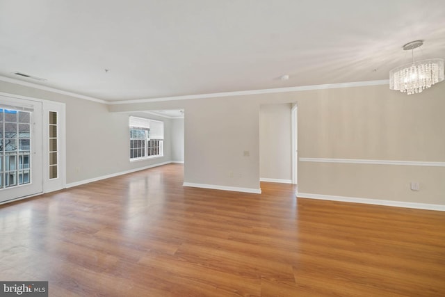 unfurnished room featuring crown molding, light hardwood / wood-style flooring, and a notable chandelier