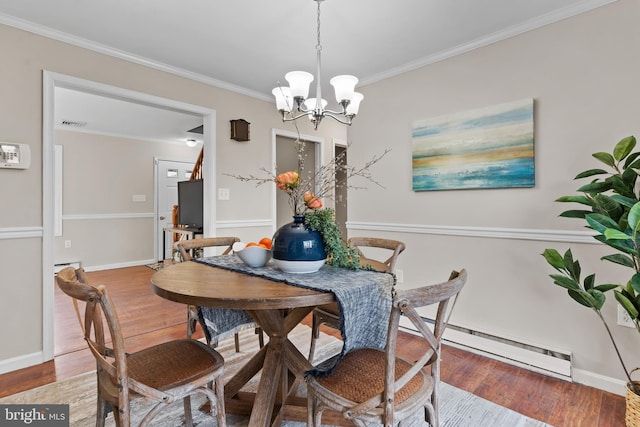 dining room featuring an inviting chandelier, hardwood / wood-style flooring, crown molding, and a baseboard heating unit