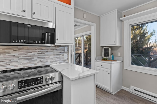 kitchen featuring white cabinetry, light stone countertops, baseboard heating, appliances with stainless steel finishes, and crown molding