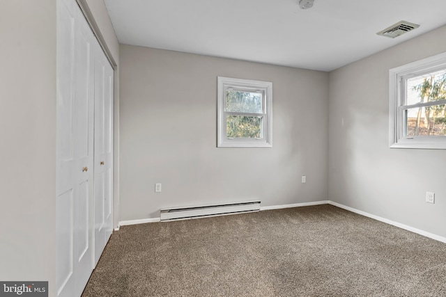 unfurnished bedroom featuring baseboard heating, carpet flooring, multiple windows, and a closet