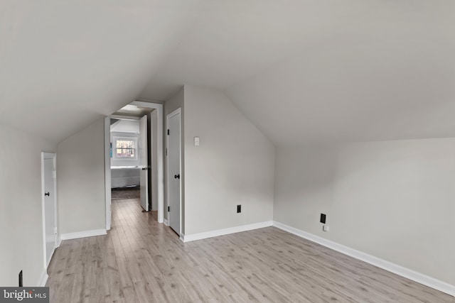 bonus room with light wood-type flooring and vaulted ceiling