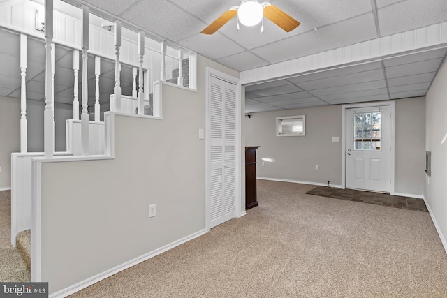 interior space featuring carpet flooring, ceiling fan, and a drop ceiling