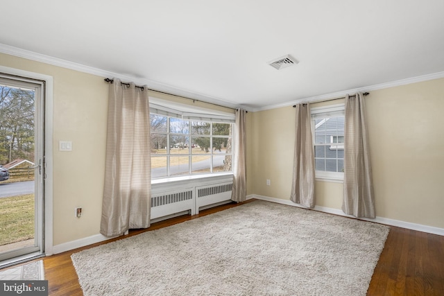 spare room with hardwood / wood-style flooring, ornamental molding, and radiator heating unit