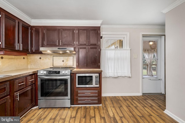 kitchen featuring appliances with stainless steel finishes, ornamental molding, light hardwood / wood-style flooring, and decorative backsplash