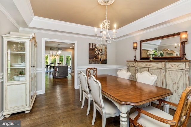 dining area featuring a notable chandelier, dark wood-type flooring, and a raised ceiling