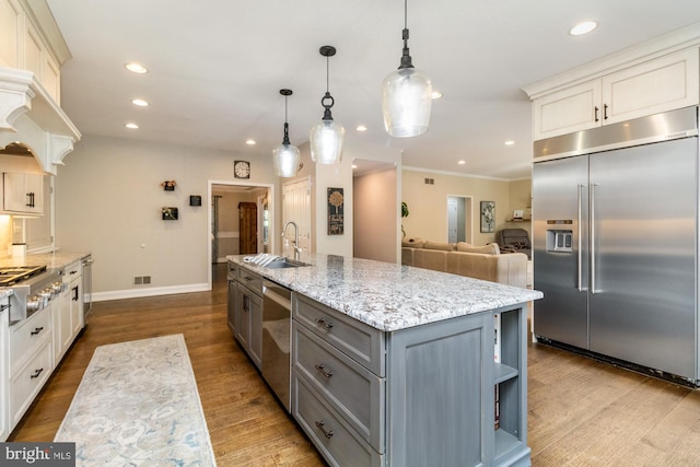 kitchen with pendant lighting, sink, gray cabinets, appliances with stainless steel finishes, and an island with sink