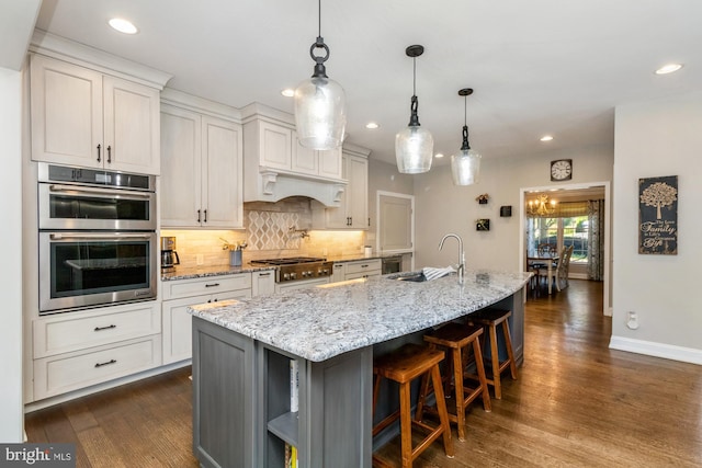 kitchen with a spacious island, sink, light stone counters, and white cabinets