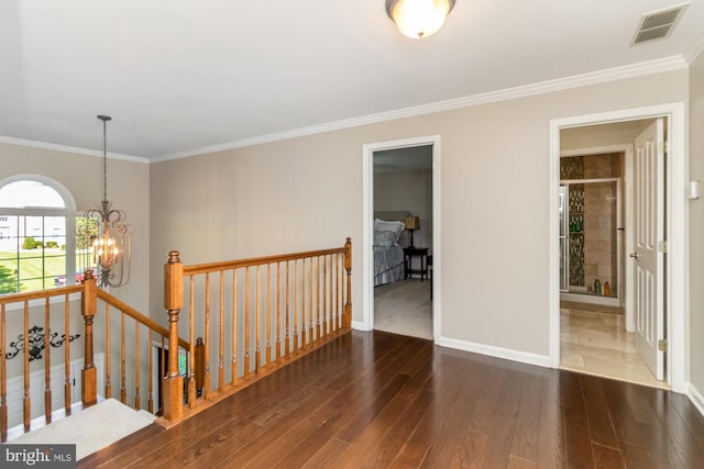 spare room featuring an inviting chandelier, ornamental molding, and dark hardwood / wood-style floors