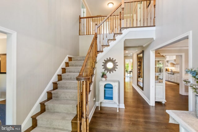 staircase featuring hardwood / wood-style flooring and a towering ceiling