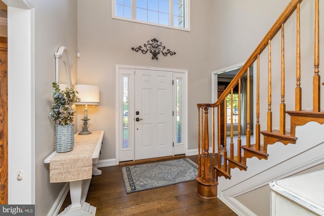 foyer entrance featuring a towering ceiling and dark hardwood / wood-style flooring