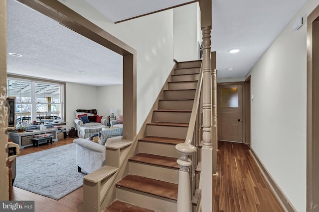 stairs featuring hardwood / wood-style floors and a textured ceiling