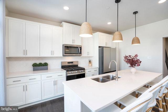 kitchen with sink, decorative light fixtures, a center island with sink, appliances with stainless steel finishes, and white cabinets