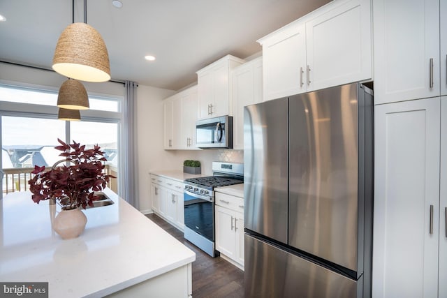 kitchen featuring pendant lighting, stainless steel appliances, dark hardwood / wood-style floors, white cabinets, and decorative backsplash