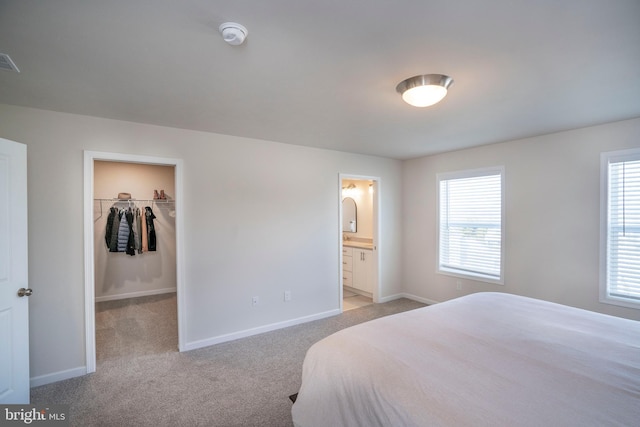 carpeted bedroom featuring connected bathroom, a walk in closet, and a closet