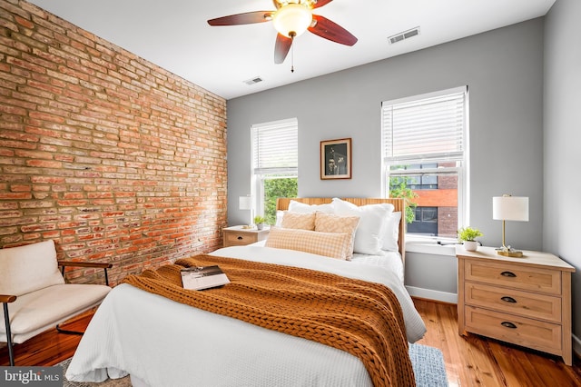 3100 E Lombard St, Baltimore, MD 21224 - bedroom with brick wall, multiple windows, light wood-style flooring, ceiling fan, and an accent wall