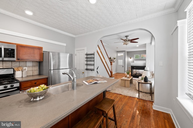 3100 E Lombard St, Baltimore, MD 21224 - kitchen with appliances with stainless steel finishes, a sink, arched walkways, a ceiling fan, and dark wood-style flooring